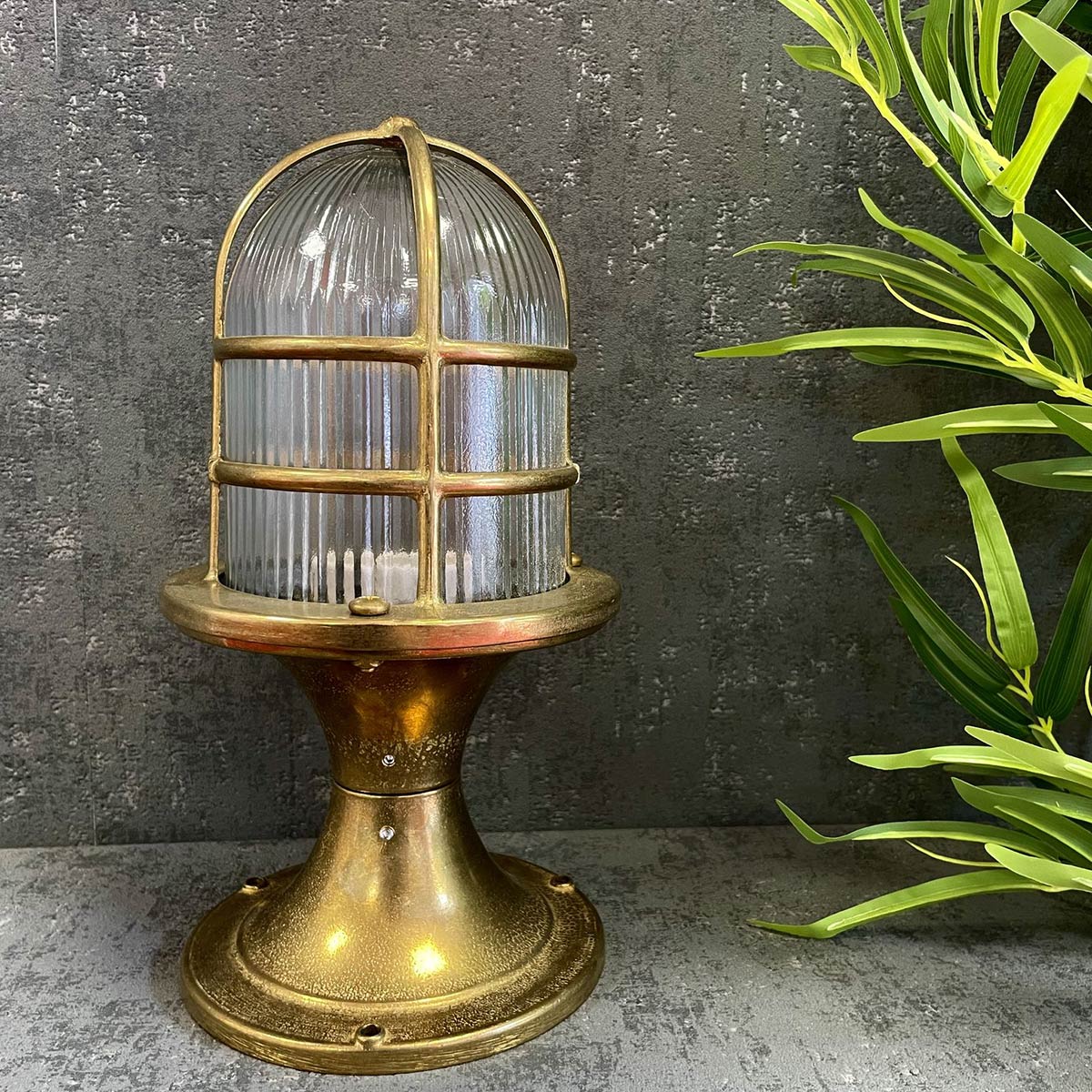 Wellington Grand post light in solid raw brass and rated IP54, in garden setting.