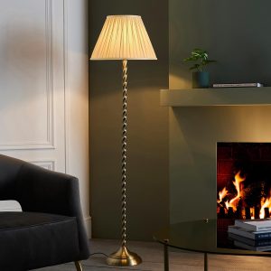 Suki plated antique brass floor lamp with ivory silk shade next to open fire in living room