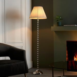 Suki polished nickel floor lamp with ivory silk shade next to open fire in living room