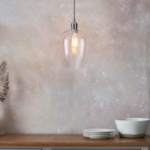 Small clear glass kitchen pendant in polished nickel, shown over side table.