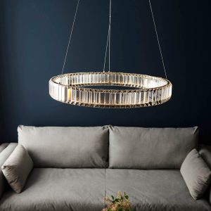Dimmable modern clear crystal LED ring ceiling pendant in chrome, shown over a lounge sofa.