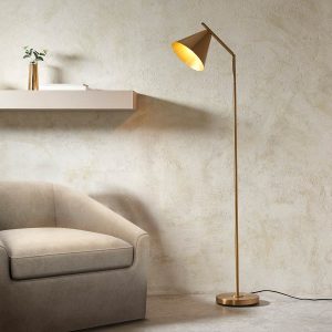 Classic adjustable floor reading lamp in antique brass with cone-shaped shade, shown in a lounge setting.