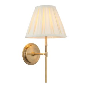 Rennes antique brass wall light with cream pleated shade on white background lit