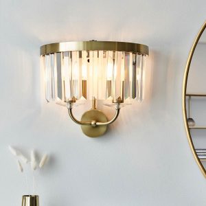 Antique brass double wall light with cut glass drops, shown alongside mirror in living room.