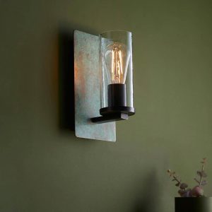 Handmade industrial wall light in plated verdigris bronze, shown on olive painted wall.