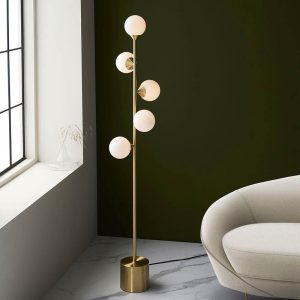 Modern satin brass floor lamp in satin brass with opal glass shades, shown in a lounge setting.