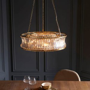 Brushed brass 6 light pendant with crystal and clear concave glass, viewed from above over a dining table.