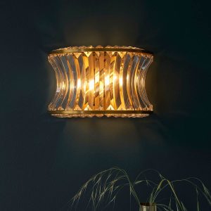 Brushed brass 2 light wall light with crystal and clear concave glass, shown on painted wall.