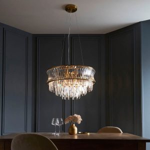 Brushed brass 9 light pendant with crystal and clear concave glass, shown over a dining room table.