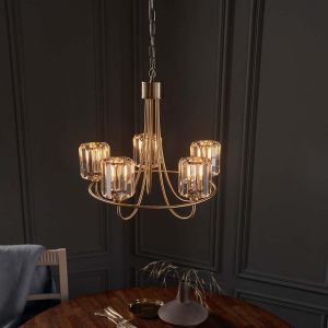 Berenice 5 light antique brass chandelier hanging over dining room table