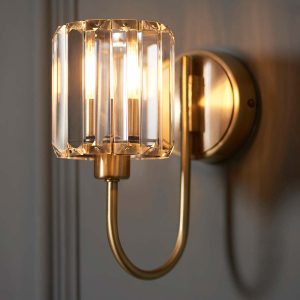Berenice antique brass wall light on grey panelled wall