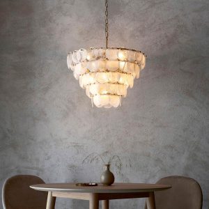Tiered 9 light white swirl glass pendant in painted antique gold, shown over a dining table.