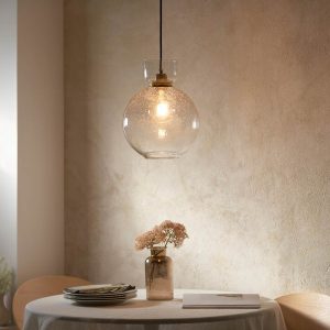 High quality kitchen pendant with clear bubble glass shade and brass plated metalwork, shown overs a dining room table.