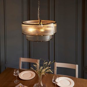 Ridgeton 5 light tiered pendant in antique brass with clear ribbed glass shade, shown over dining room table.