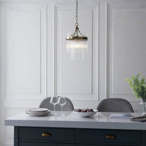 Marietta single light pendant in antique brass with clear glass rods, shown over breakfast table.