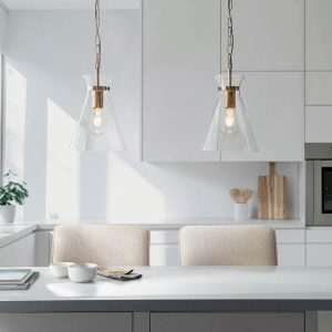 Harlow single light pendant in aged brass with clear glass shade, shown as a pair over a kitchen breakfast bar.