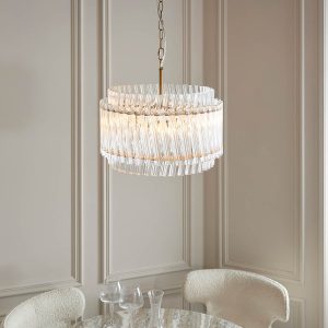 Exquisite 3 light pendant in brushed aged brass with glass rods, shown over a dining room table.