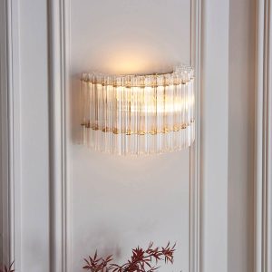 Exquisite 2 light wall light in brushed aged brass with glass rods, shown on panelled room wall.