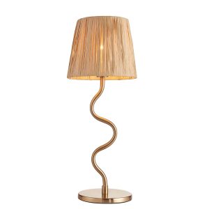 Wriggle table lamp in brushed aged brass finish with raffia shade on white background, lit.