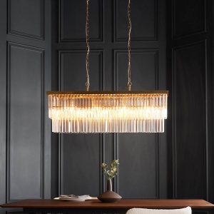 Conaston 4 light aged brass linear pendant with glass prisms, shown over a dining room table.