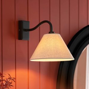 Knole classic matt black wall light with natural faux linen shade, angled view on salmon panelled wall.