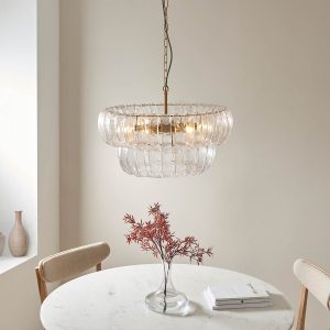 Montrose 6 light pendant in brushed aged brass with handmade curved glass decoration, shown over a dining room table.