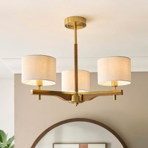 Heathcliff 3 light semi flush ceiling light in brushed aged brass and wood with natural faux linen shades, on living room ceiling.