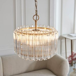 Valentina 3 light pendant in brushed aged brass with large glass rods, shown fitted over a sofa.
