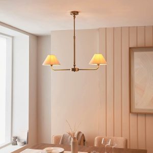 Lille antique brass 2 light linear pendant with natural faux linen shades, shown over a dining room table.