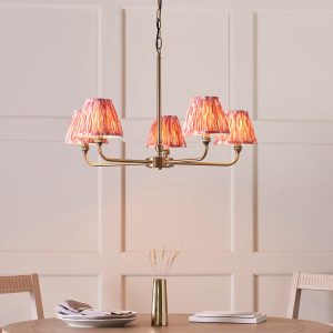 Lille 5 light antique brass chandelier with pink Ikat shades, shown over a dining room table.