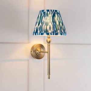 Lille single antique brass wall light with blue Ikat shade, shown in panelled room.
