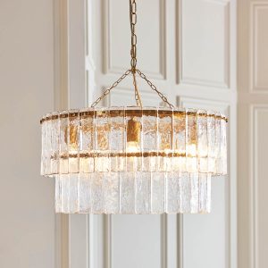 Karine 5 light tiered pendant in brushed aged brass with textured handmade glass, shown in panelled room.