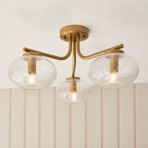 Jacob 3 light semi flush in aged brass with bubble glass shades, shown in room setting.