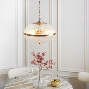 Somerset 3 light ribbed glass globe pendant in vintage brass, shown over dining room table.