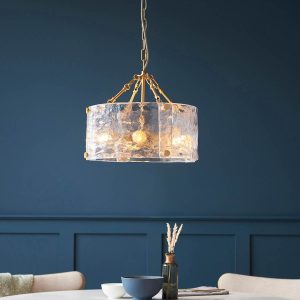Keller 4 light pendant in aged brass with textured handmade glass, shown over dining room table.