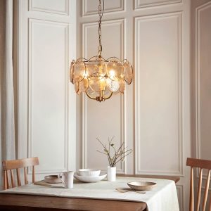 Aged brass 3 light pendant with handmade champagne glass, shown over a dining room table.