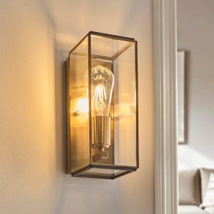 Hammond indoor box wall lantern in antique brass with clear glass panels, shown on living room wall.
