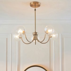 Hague 5 light chandelier in antique brass with twisted clear glass shades, shown in room setting.