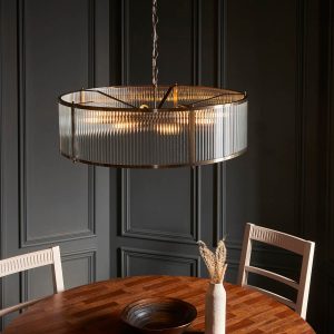 Large Ridgeton 8 light pendant in antique brass with clear ribbed glass shade, shown over a dining room table.