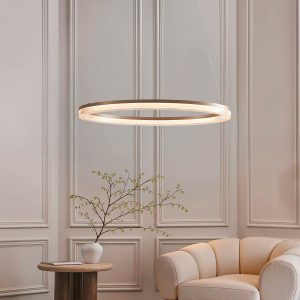 Dimmable brushed gold finish modern LED hoop ceiling pendant, shown over a lounge chair.