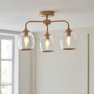 Ashcroft 3 light semi flush in brushed aged brass with clear glass goblet shades, shown on room ceiling.