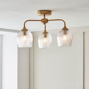 Ashcroft 3 light semi flush in brushed aged brass with clear ribbed glass goblet shades, shown on room ceiling.