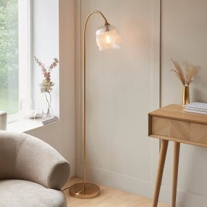 Ashcroft floor lamp in brushed aged brass with clear ribbed glass goblet shade, shown in a siting room.