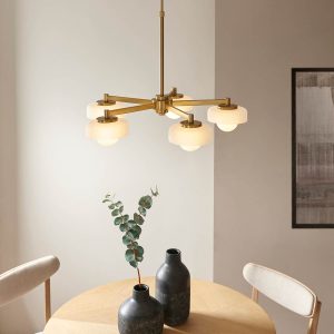 Boss 5 light pendant ceiling light in brushed aged brass, shown over a dining room table.