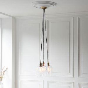 3 light cluster pendant in antique brass with clear glass goblet shades, full height in panelled room.