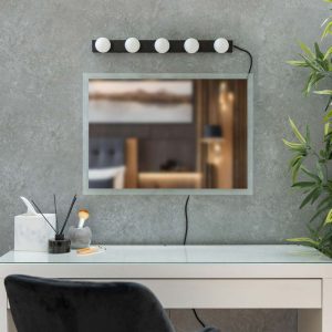 Hollywood style plug in wall light in black, shown unlit above mirror