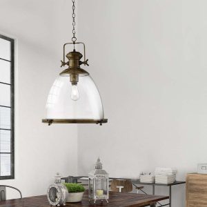 Large industrial pendant light in antique brass with clear glass shade over dining table