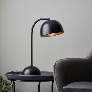 Brodey industrial style table lamp in matt black, next to chair on lounge table