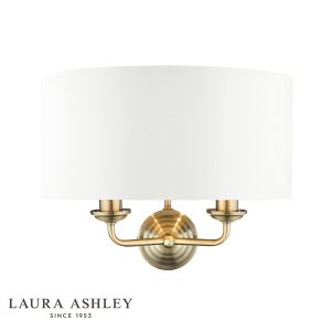 Sorrento 2 light wall light in antique brass finish ivory faux silk shade on white background, lit.