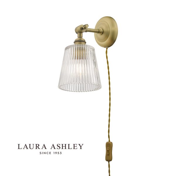 Laura Ashley Callaghan plug in wall light in antique brass on white background, lit.
